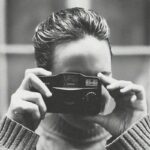 Femme qui prend une photo avec un appareil argentique compact