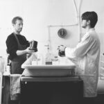 Père et fils qui agitent leurs cuves de développement de part et d'autre de l'évier du labo