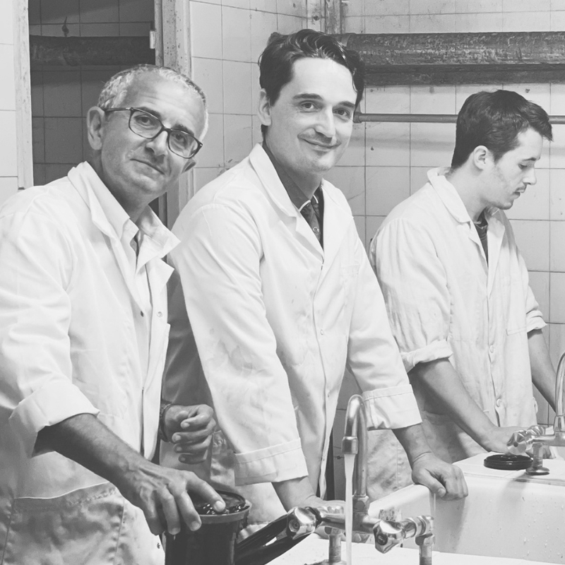 Trois hommes souriants en blouse blanche devant les éviers du labo