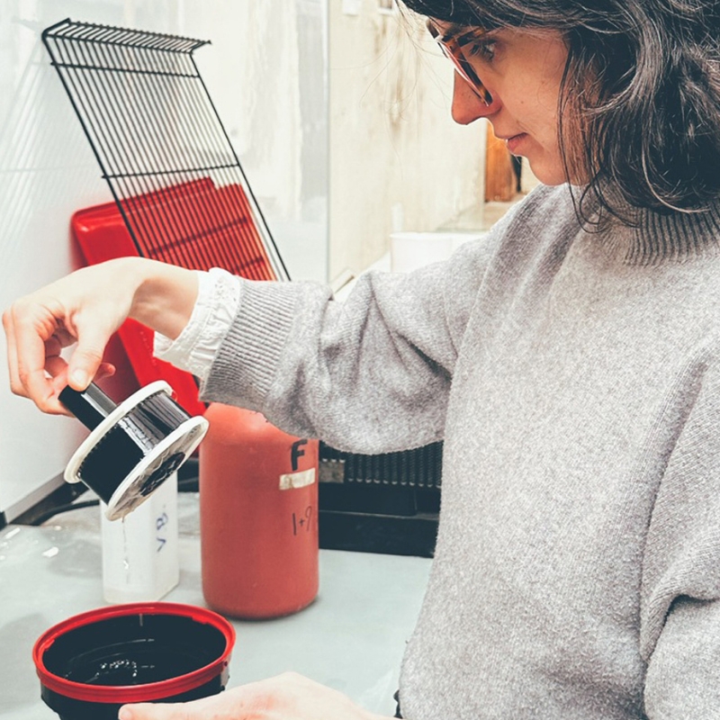 Femme qui place une spire dans sa cuve de développement, à côté des flacons de chimie