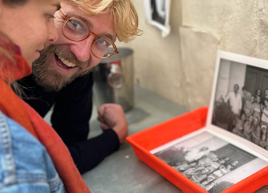 Deux membres du Print-Club regardent des tirages noir et blanc posés dans une cuvette rouge, lors d’une lecture de portfolio